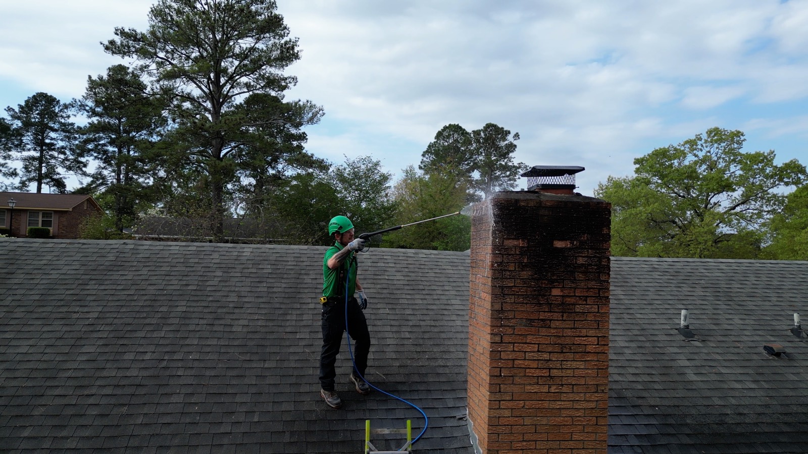 Chimspector technician soft-washing a brick chimney