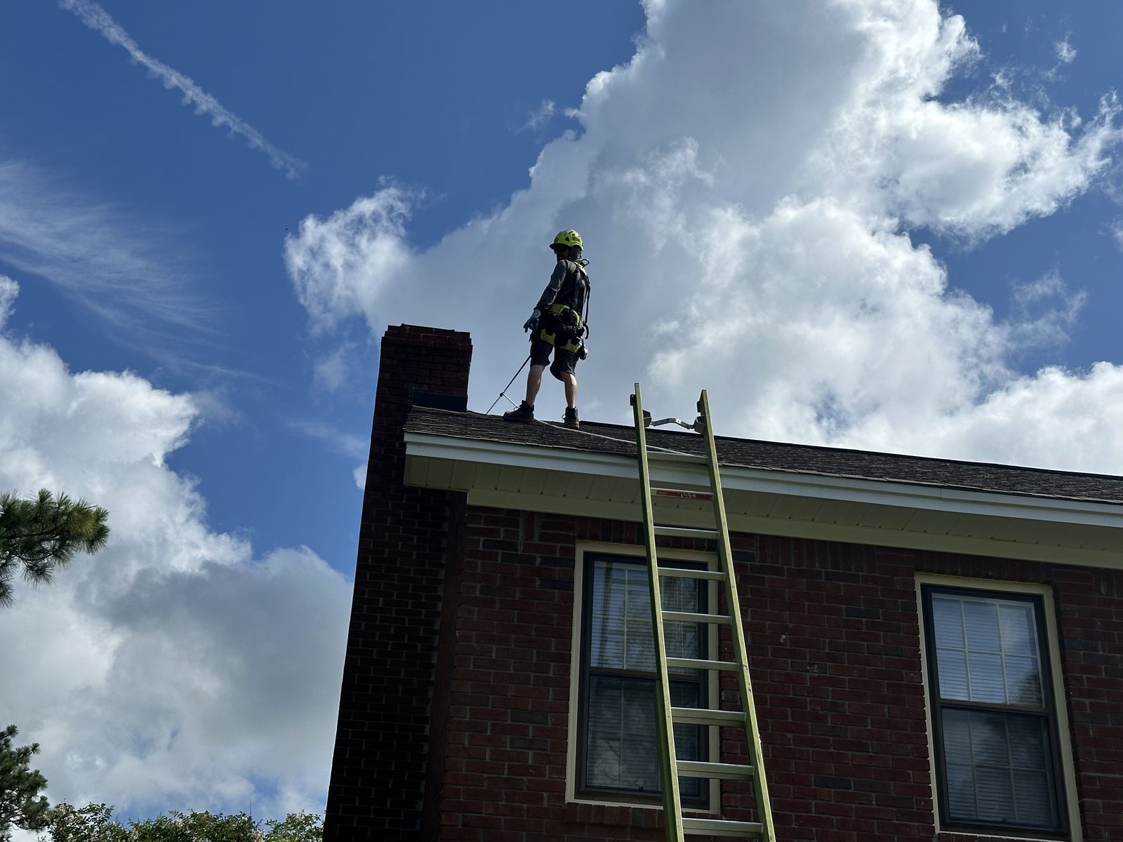 Technician on a ladder at a brick chimney