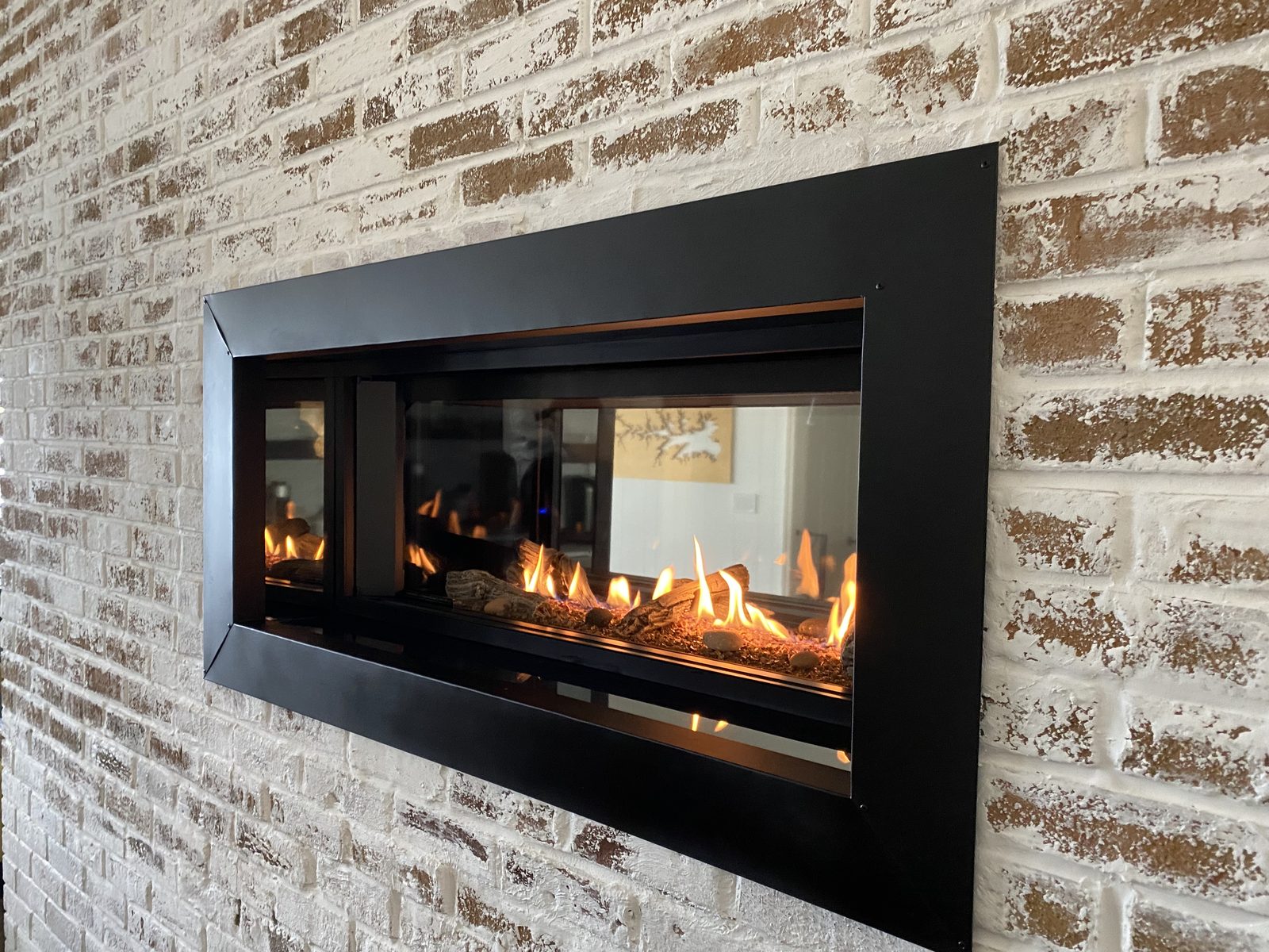 See-through linear gas fireplace in a brick wall