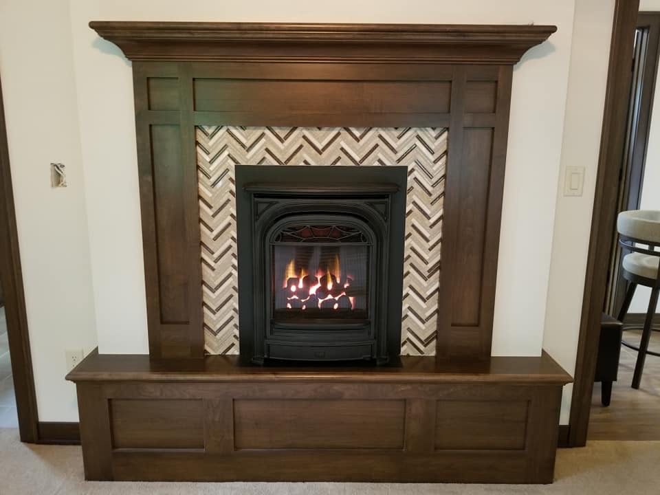 Valor portrait gas insert with a herringbone tile surround and wood mantel
