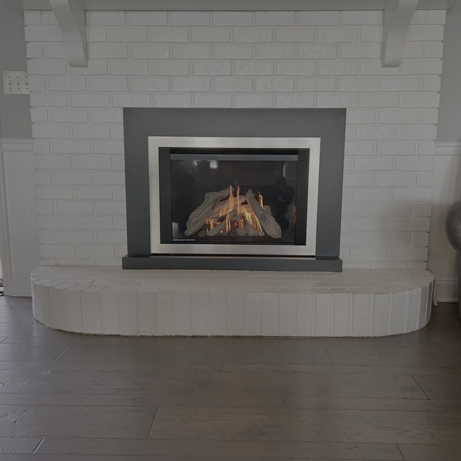 Gas insert installed in a painted white brick fireplace